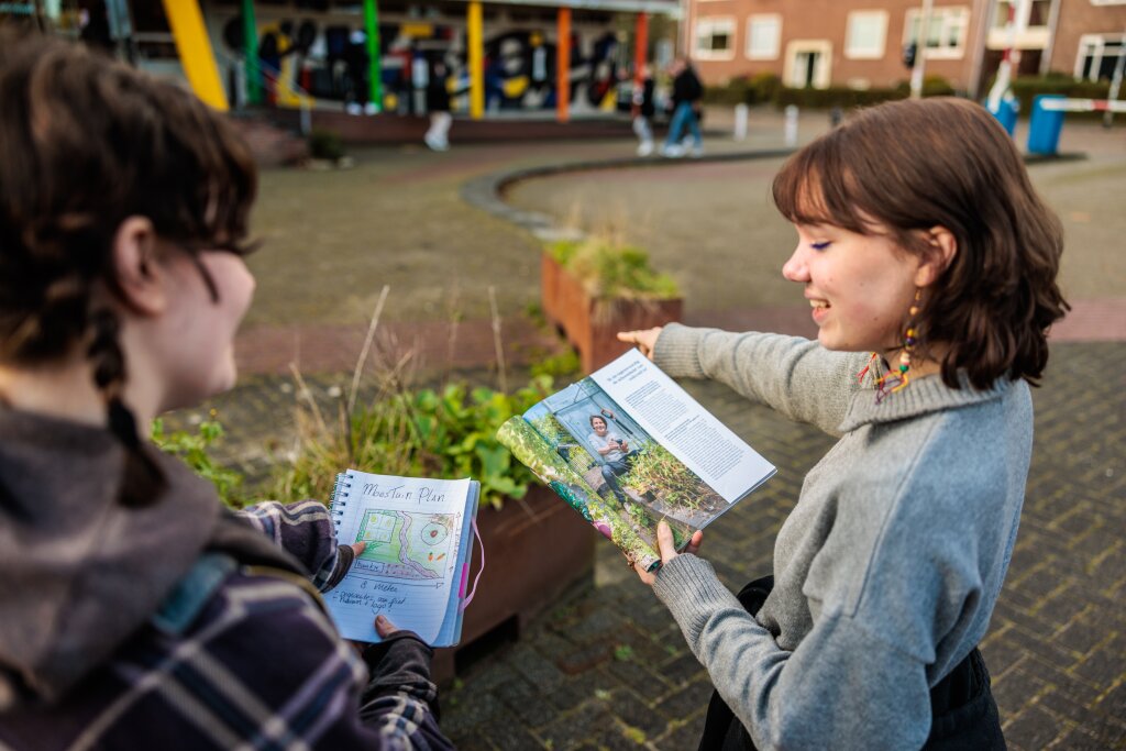Studenten bespreken een plan voor een moestuin op het schoolplein van Noorderpoort Kunst & Multimedia.