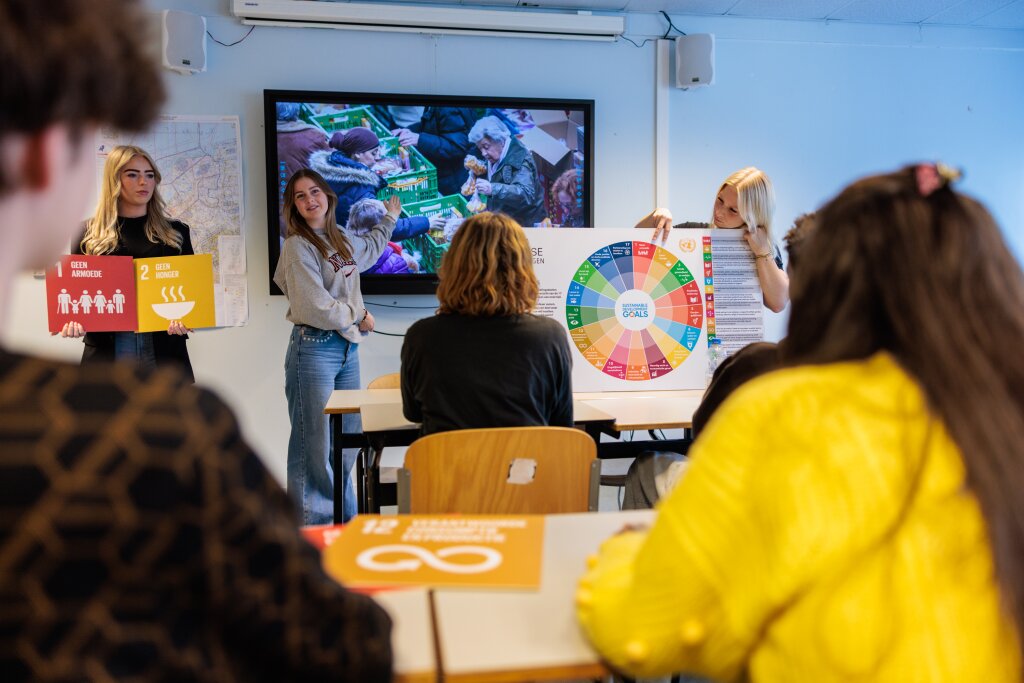 Studenten presenteren de Sustainable Development Goals in een klaslokaal.